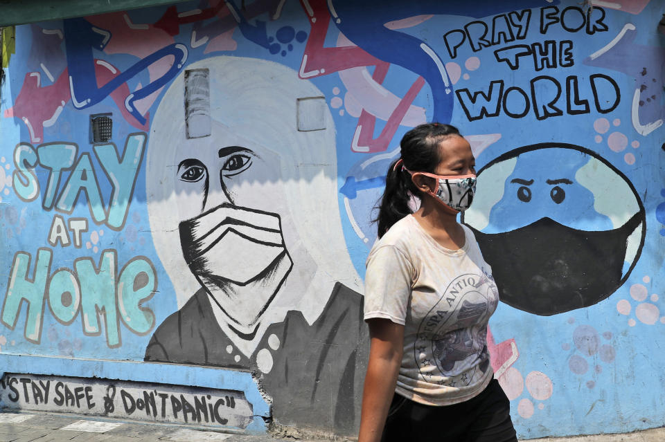 A woman walks past a coronavirus-themed mural in Tangerang, Indonesia, Tuesday, Sept. 29, 2020. (AP Photo/Tatan Syuflana)