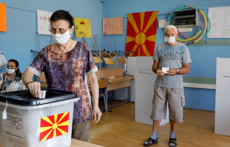 A woman wearing a face mask casts her ballot at a polling station during the general election, in Strumica