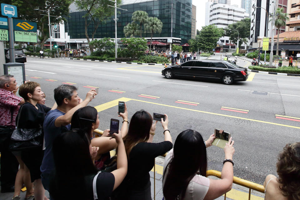 People take photographs as&nbsp;Kim's motorcade leaves the St. Regis hotel.