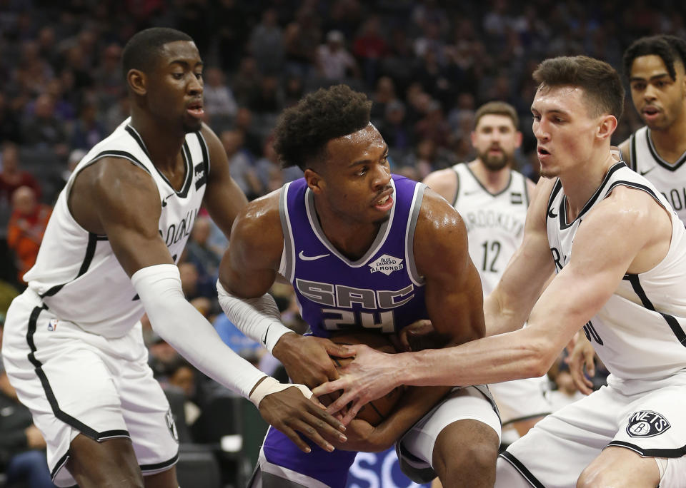 Sacramento Kings guard Buddy Hield, center, is double-teamed by Brooklyn Nets' Caris LeVert, left, and Rodions Jurucs, right, during the first quarter of an NBA basketball game Tuesday, March 19, 2019, in Sacramento, Calif. (AP Photo/Rich Pedroncelli)