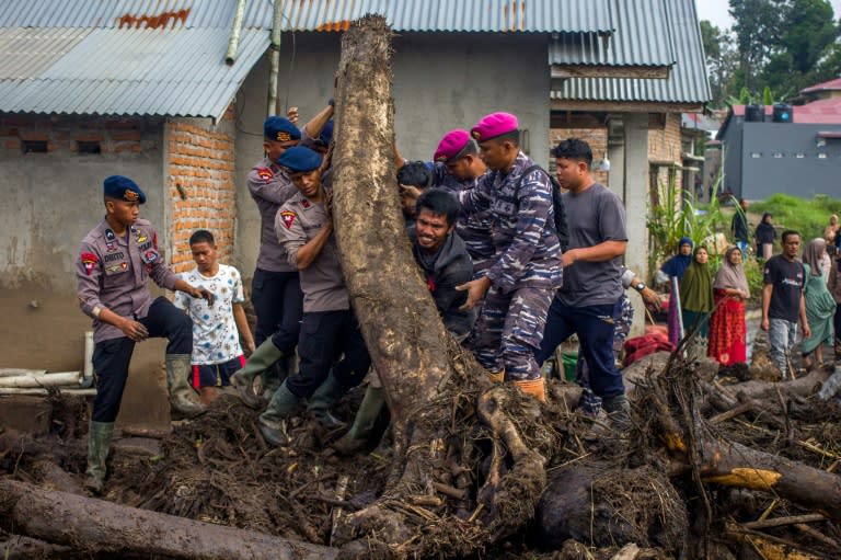 Rescue teams and people move logs that had washed into residential areas in western Indonesia (REZAN SOLEH)