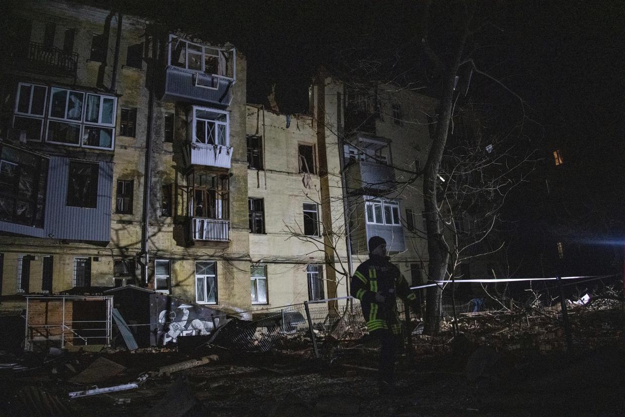 An emergency worker walks in front of a residential building which was hit by a Russian rocket in the city centre of Kharkiv (AP)