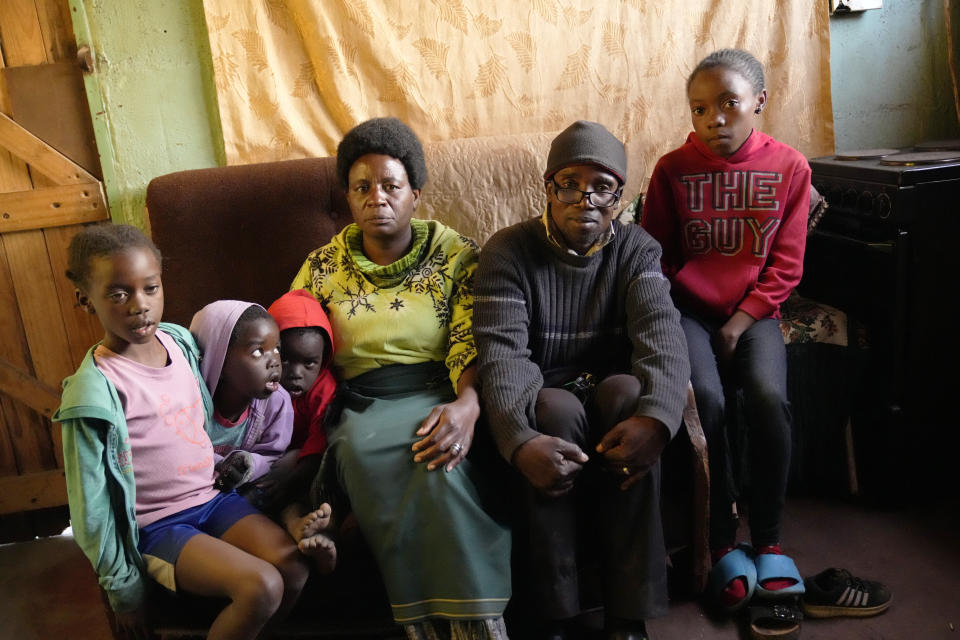 Jeffrey Carlos,centre,poses for a photo with some of his family members on the outskirts of Harare on Wednesday, Aug, 3, 2022. Carlos, a father of three, says he gets about $100 dollars a month from his job as an overnight security guard for a church and the bar next door. Rising prices and a fast-depreciating currency have pushed many Zimbabweans to the brink, reminding people of when the southern African country faced world-record inflation of 5 billion % in 2008.(AP Photo/Tsvangirayi Mukwazhi)