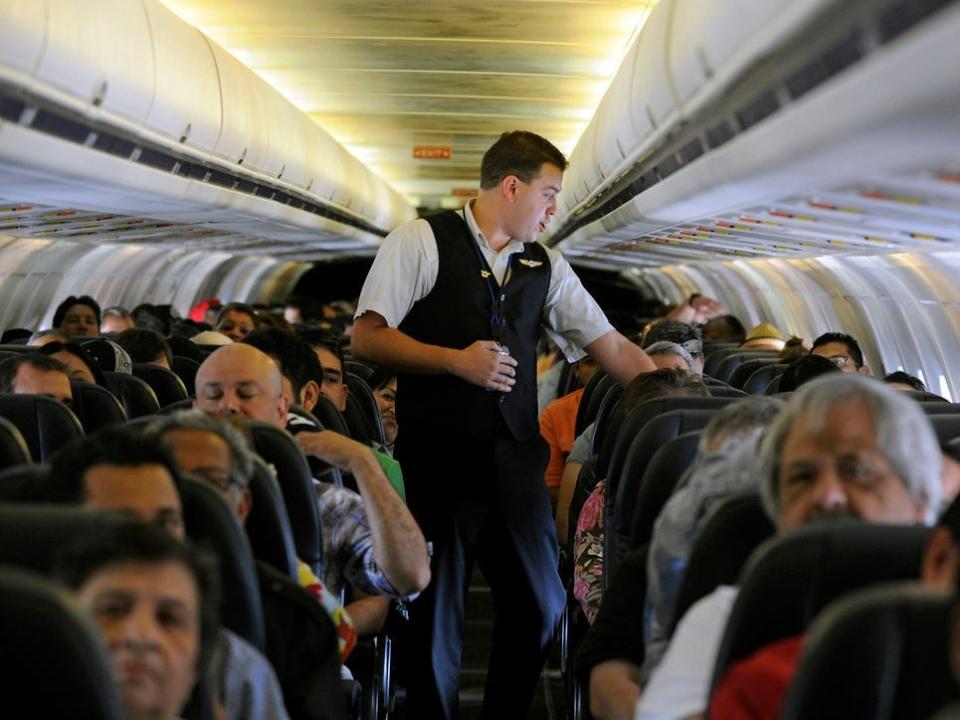 Allegiant Air flight attendant Chris Killian talking to passengers as the plane pushes back from the gate at Las Vegas airport.