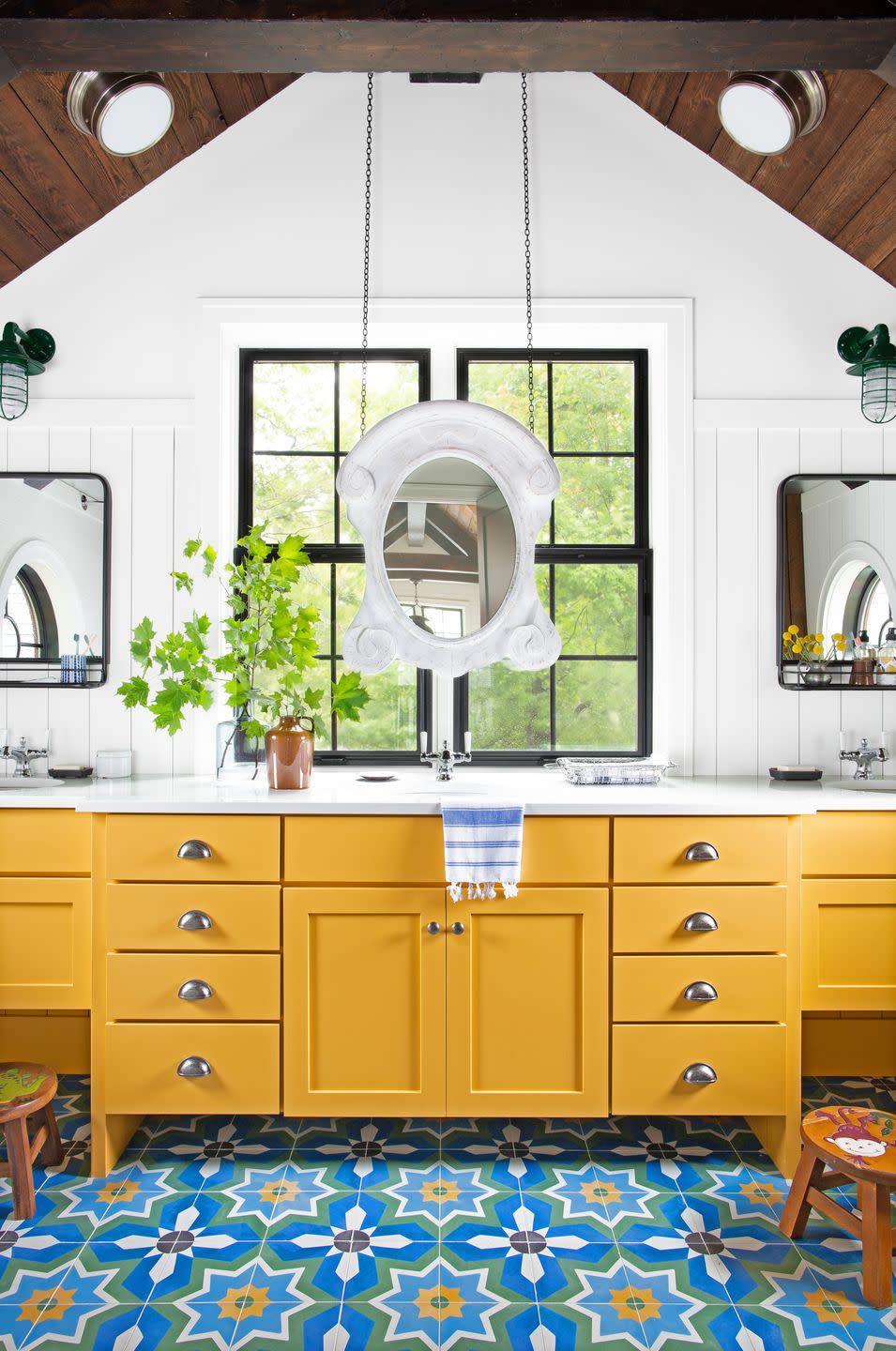 bathroom with white walls, warm yellow cabinetry, and tiled floors in a blue green and yellow pattern