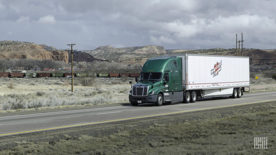 A green tractor pulling a white Heartland Express trailer