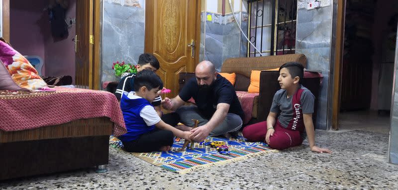 Local worker Mohammed Haider plays with his children at his home in Basra