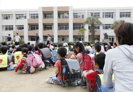 Students sit on a playground after they were evacuated from school building after an earthquake at Ikeda elementary school in Ikeda, Osaka prefecture, western Japan, in this photo taken by Kyodo June 18, 2018. Mandatory credit Kyodo/via REUTERS