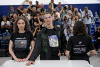 Producers Darya Bassel, left, and Yelizaveta Smith, right, wearing t-shirts that have an image of an explosion on the front and read "Sensitive Content: Russians kill Ukrainians. Do you find it offensive and disturbing to talk about this genocide?" pose with director Maksym Nakonechnyi who wears a t-shirt that reads "Free Tayra" in reference to Julia Paevska, aka Tayra, a Ukrainian medic who Russian forces have taken captive at the photo call for the film 'Butterfly Vision' at the 75th international film festival, Cannes, southern France, Wednesday, May 25, 2022. (AP Photo/Daniel Cole)