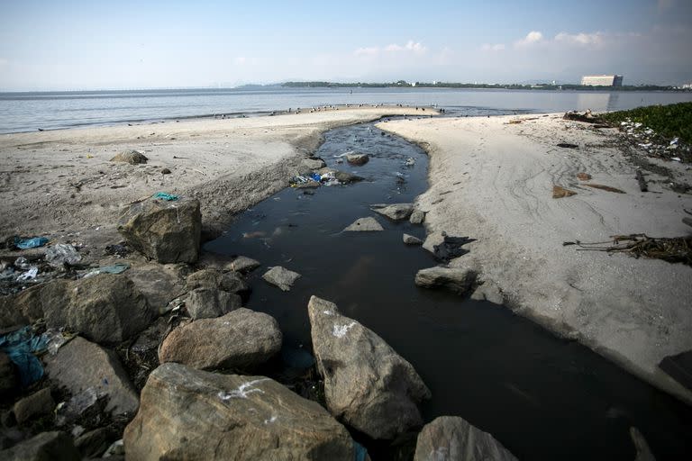 Las aguas residuales fluyen a través de la playa Galeao hacia el océano en Río de Janeiro, Brasil