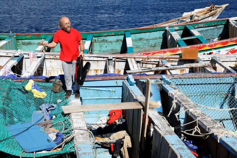 Fernando Gutierrez, the head of the port's fishermen union observes the interior of abandoned wooden boats used by migrants in the port of La Restinga