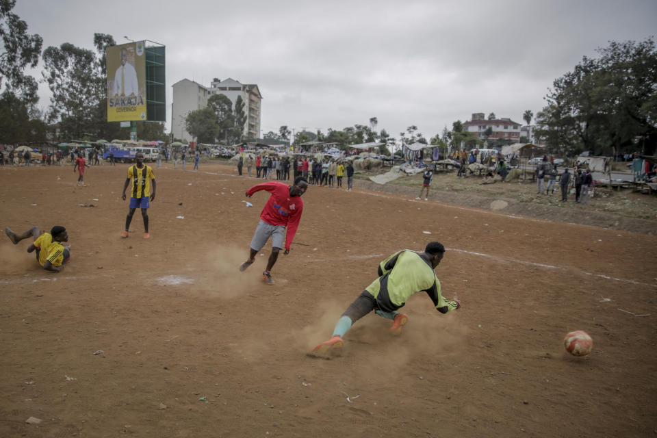 Youths play soccer on a dirt pitch in the Kibera low-income neighborhood of Nairobi, Kenya Monday, Aug. 1, 2022. Kenya's Aug. 9 election is ripping open the scars of inequality and corruption as East Africa's economic hub chooses a successor to President Uhuru Kenyatta. (AP Photo/Brian Inganga)