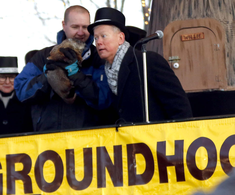 FILE - Mayor Brian Sager, right, listens to Woodstock Willie, who is held by Mark Szafran, as Woodstock Willie the groundhog emerged from his slumber and viewed his shadow, Friday, Feb. 2, 2018, in Woodstock, Ill. (Brian Hill/Daily Herald via AP, File)