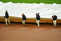 Grounds crew members place a tarp over the infield at Oriole Park at Camden Yards during a rain delay in the eighth inning of a baseball game between the Baltimore Orioles and the Toronto Blue Jays, Monday, Oct. 3, 2022, in Baltimore. (AP Photo/Julio Cortez)