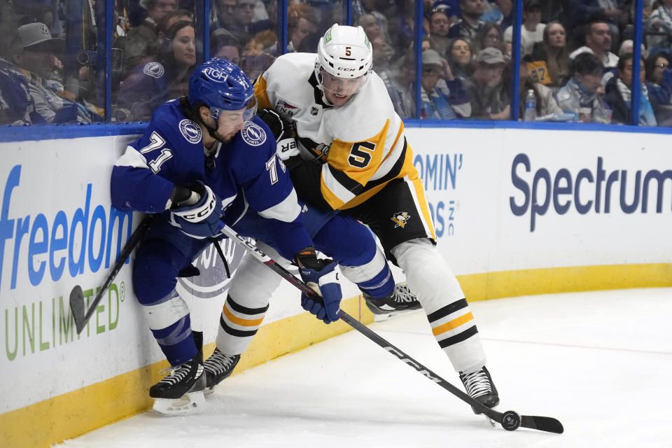 Pittsburgh Penguins defenseman Ryan Shea (5) ties up Tampa Bay Lightning center Anthony Cirelli (71) along the dasher during the second period of an NHL hockey game Wednesday, Dec. 6, 2023, in Tampa, Fla. (AP Photo/Chris O'Meara)