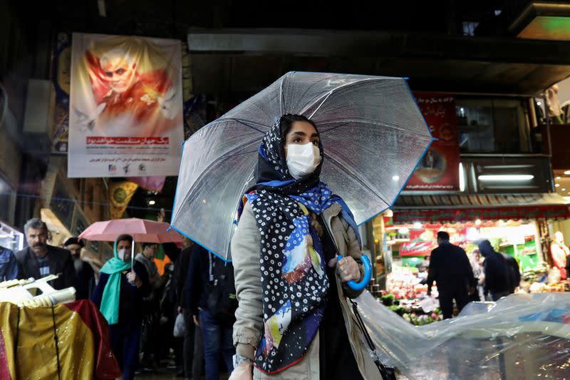 FILE PHOTO: An Iranian woman wears a protective face mask and gloves, amid fear of coronavirus disease (COVID-19), as she walks at Tajrish market, ahead of the Iranian New Year Nowruz, March 20, in Tehran