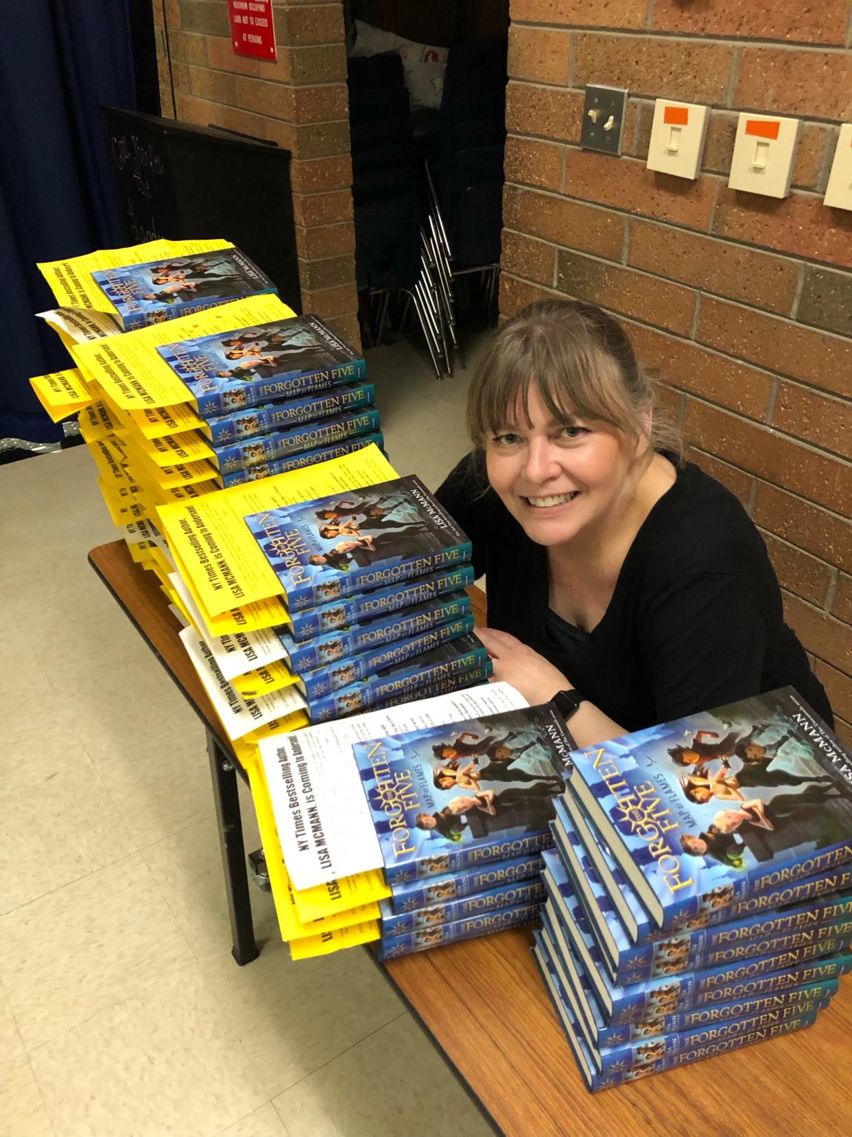 Lisa McMann poses with copies of "Map of Flames," the first book in "The Forgotten Five" series.