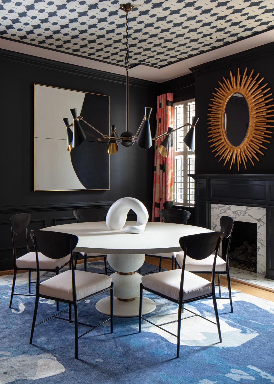The starting point for the dining room was Benjamin Moore Black Berry walls. The deep blue-black provided a dramatic backdrop that allowed patterns to leap off the walls, ceiling, and floor. Lindsay’s Navy White Grasscloth was used to create a faux tray ceiling accented with Farrow & Ball Calamine paint. Jill pumped up the volume in the dining room with the artist’s Blue Wool Silk Rug and Porter Teleo draperies, Oly Studio dining chairs, a Mr. Brown London honed Carrara marble table, a Julian Chichester light fixture, and a mirror by Made Goods.
