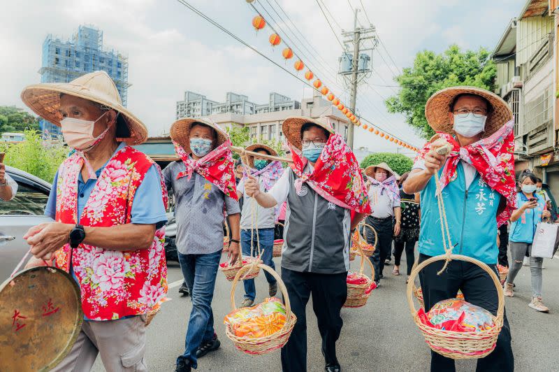 ▲鄭文燦和民眾一起戴花布斗笠、肩挑扁擔籮筐共同挑擔踩街，展現客家傳統文化，並至義民廟祭祀，表達對義民爺信仰的虔誠。（圖／桃園市政府提供）