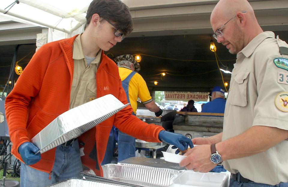 Boys Scout Benjamin Parr fills a clamshell held by Bedford Boy Scout Troop 332 Scoutmaster Ryan Turner at the Bedford Lion's Club Pancake Festival Saturday, May 4, 2024, at the Thornton Park Pavilion.