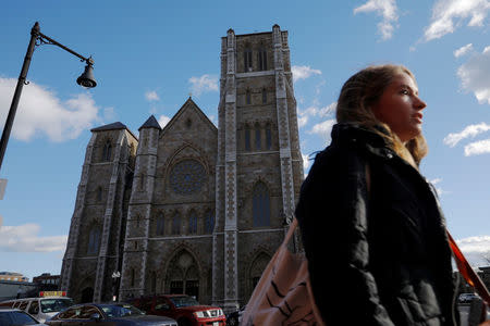 A pedestrian passes the Cathedral of the Holy Cross, where Cardinal Bernard Law, the former Archbishop of Boston who resigned in 2002 in disgrace after covering up years of sexual abuse of children, served in Boston, Massachusetts, U.S., December 20, 2017. REUTERS/Brian Snyder