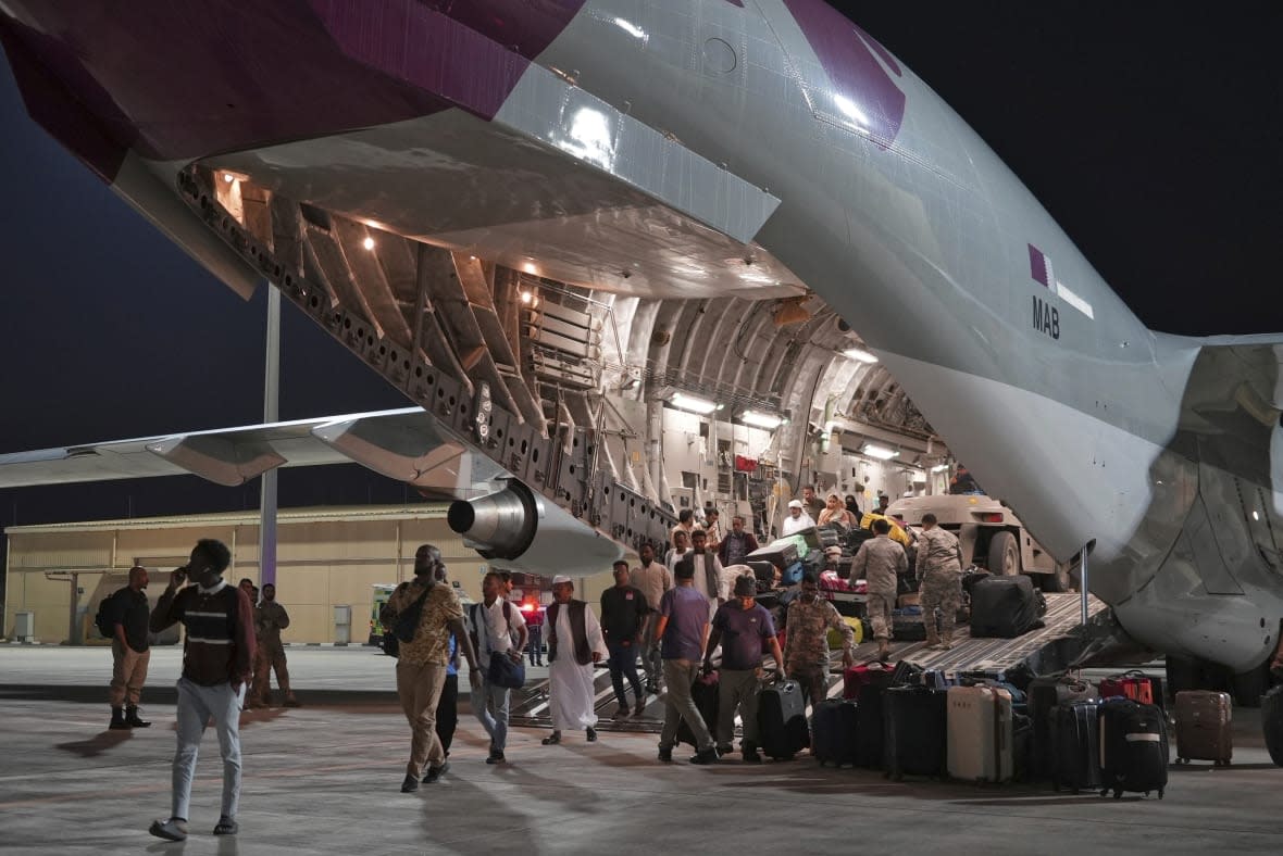 Evacuees flown out of Sudan disembark a Qatari C-17 Globemaster at Al Udeid Air Base, Qatar, Saturday, May 6, 2023. Qatar flew a relief flight into Sudan, carrying some 40 tons of food and leaving with 150 evacuees early Saturday as fighting continues between two generals vying for power in the African nation. (AP Photo/Lujain Jo)