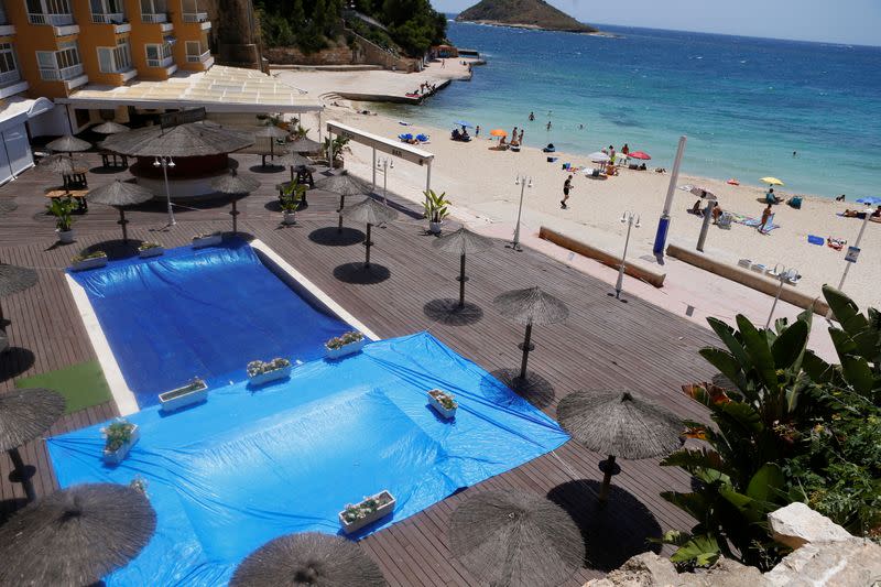 The swimming pool of a hotel is seen closed as people sunbathe in Magaluf beach