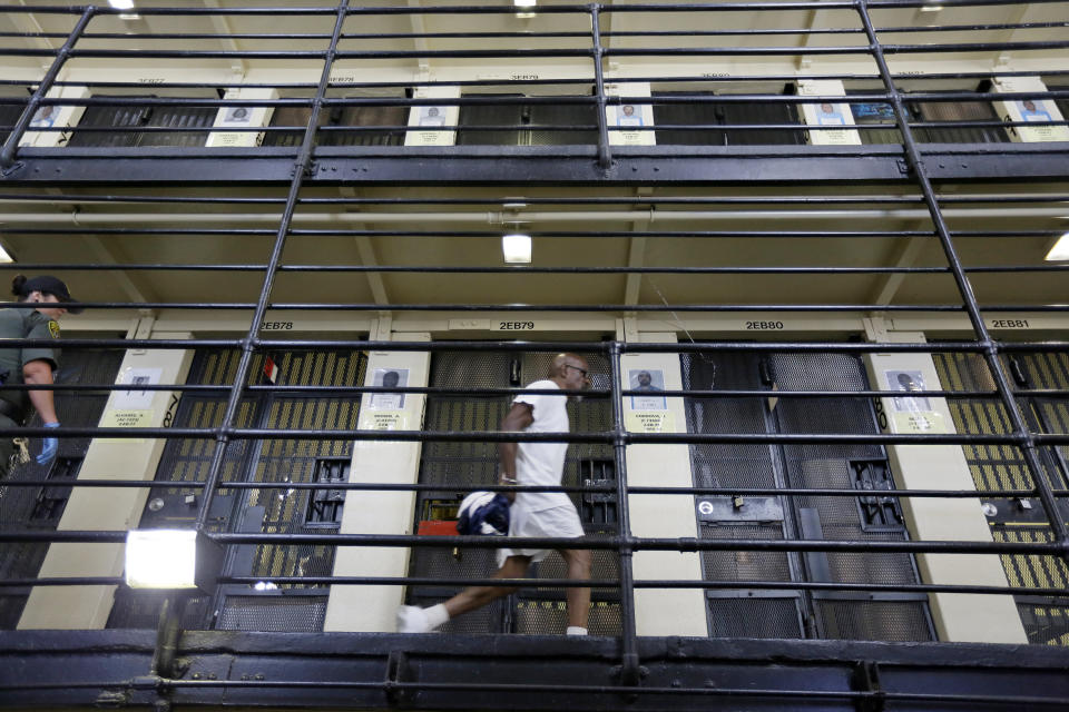 FILE - In this Aug. 16, 2016, file photo, a condemned inmate walks along the east block of death row at San Quentin State Prison in San Quentin, Calif. The California Labor and Workforce Development Agency confirmed Tuesday, Dec. 1, 2020, that California has sent about $400 million in unemployment benefits to state prison inmates. In all records show 31,000 inmates have applied for benefits and about 20,800 were paid $400 million. A group of local and federal prosecutors said 133 inmates on death row were named in claims. (AP Photo/Eric Risberg, File)