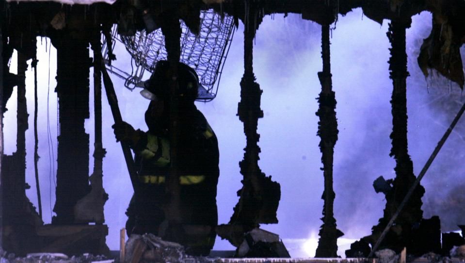 Firefighters work in the charred remnants of a house fire on Buxton Road in North Smithfield in January 2003.