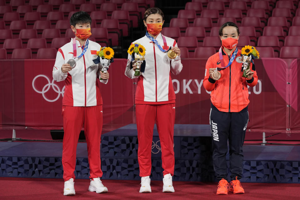 China's Chen Meng, center, holds her gold medal, China's Sun Yingsha, left, silver medal, and Japan's Mima Ito, bronze medal, pose for photographers in the table tennis women's singles at the 2020 Summer Olympics, Thursday, July 29, 2021, in Tokyo. (AP Photo/Kin Cheung)