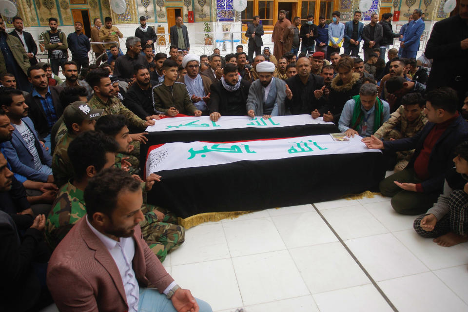 Mourners pray over the flag-draped coffins of two fighters of the Popular Mobilization Forces who were killed during the US attack on against militants in Iraq, during their funeral procession at the Imam Ali shrine in Najaf, Iraq, Saturday, March 14, 2020. The U.S. launched airstrikes on Thursday in Iraq, targeting the Iranian-backed Shiite militia members believed responsible for a rocket attack that killed and wounded American and British troops at a base north of Baghdad. (AP Photo/Anmar Khalil)