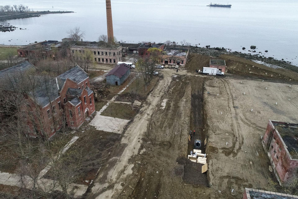 Workers wearing personal protective equipment bury bodies in a trench on Hart Island, Thursday, April 9, 2020, in the Bronx borough of New York. On Thursday, New York City’s medical examiner confirmed that the city has shortened the amount of time it will hold on to remains to 14 days from 30 days before they will be transferred for temporary internment at a City Cemetery. Earlier in the week, Mayor Bill DeBlasio said that officials have explored the possibility of temporary burials on Hart Island, a strip of land in Long Island Sound that has long served as the city’s potter’s field. (AP Photo/John Minchillo)