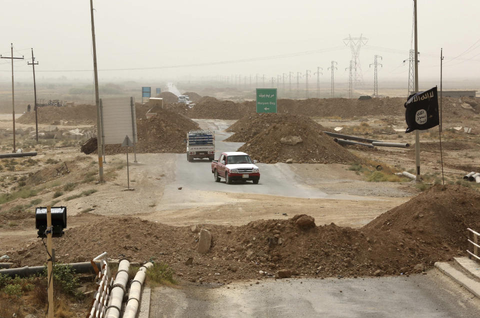 FILE - Islamic State militants passing a checkpoint bearing the group's trademark black flag in the village of Maryam Begg in Kirkuk, 290 kilometers (180 miles) north of Baghdad, Iraq, Sept. 29, 2014. Ten years after the Islamic State group declared its caliphate in large parts of Iraq and Syria, the extremists now control no land, have lost many prominent founding leaders and are mostly away from the world news headlines. (AP Photo/Hadi Mizban, File)