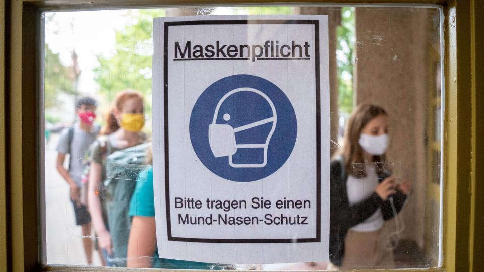 Schüler betreten hinter einem Plakat mit der Aufschrift «Maskenpflicht» am ersten Tag nach den Sommerferien den Eingang zum Rheingau Gymnasium in Berlin.