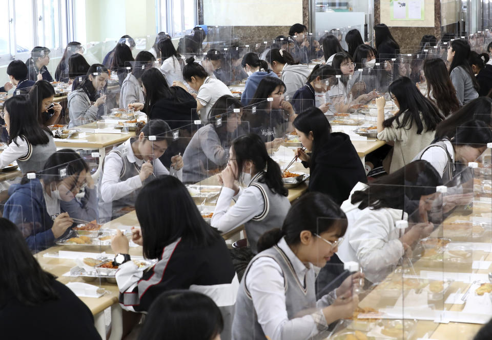 Senior students eat lunch at tables equipped with plastic barriers to prevent possible spread of the new coronavirus in the cafeteria at Jeonmin High School in Daejeon, South Korea, Wednesday, May 20, 2020. South Korean students began returning to schools Wednesday as their country prepares for a new normal amid the coronavirus pandemic. (Kim Jun-beom/Yonhap via AP)