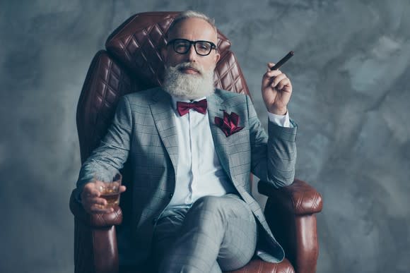 A rich old man sitting in a leather chair.