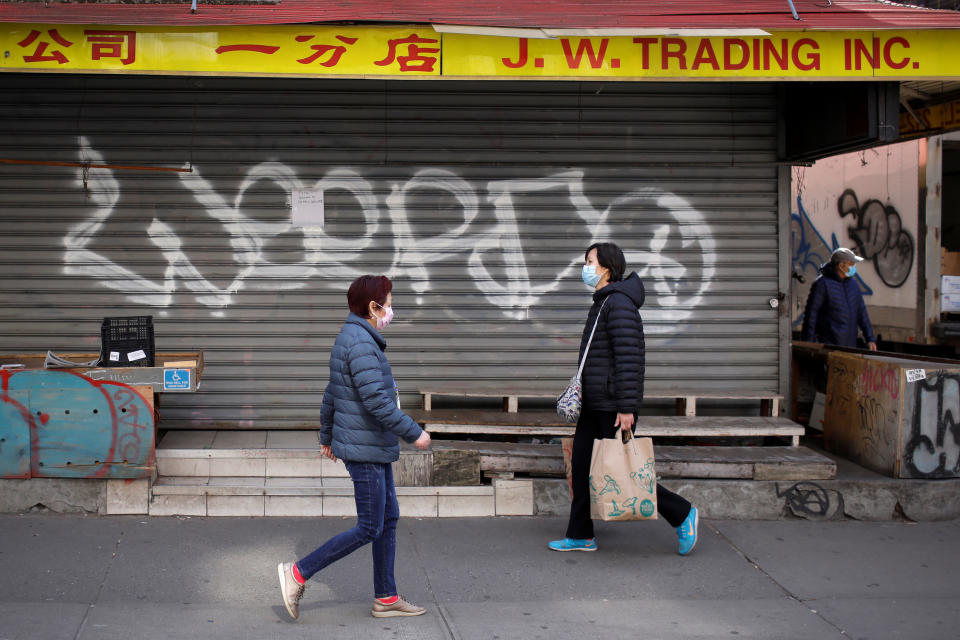 People in masks walk past a closed shop in the Chinatown neighborhood of Manhattan during the coronavirus outbreak in New York City, New York, U.S., March 18, 2020. REUTERS/Mike Segar