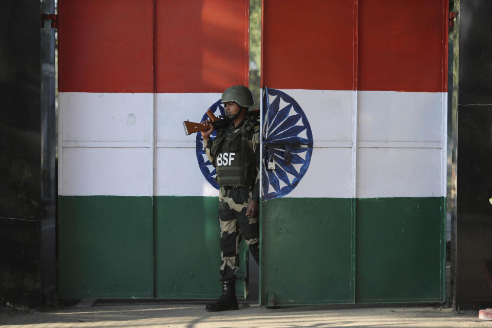 FILE - In this Jan. 23, 2020, file photo, an Indian Border Security Force soldier walks through a gate painted with the Indian flag at the India-Pakistan border at Suchet Garh in Ranbir Singh Pura, about 27 kilometers (17 miles) south of Jammu, India. The Line of Control, a highly militarized de facto border that divides the disputed region between the two nuclear-armed rivals India and Pakistan, and a site of hundreds of deaths, is unusually quiet after the two South Asian neighbors agreed in February, 2021, to reaffirm their 2003 cease-fire accord. (AP Photo/Channi Anand, File)