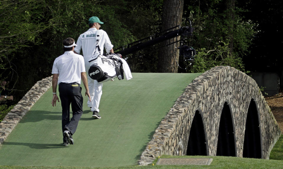 Bubba Watson walks across the Hogan Bridge with his caddie Ted Scott during the fourth round of the Masters golf tournament Sunday, April 13, 2014, in Augusta, Ga. (AP Photo/Darron Cummings)