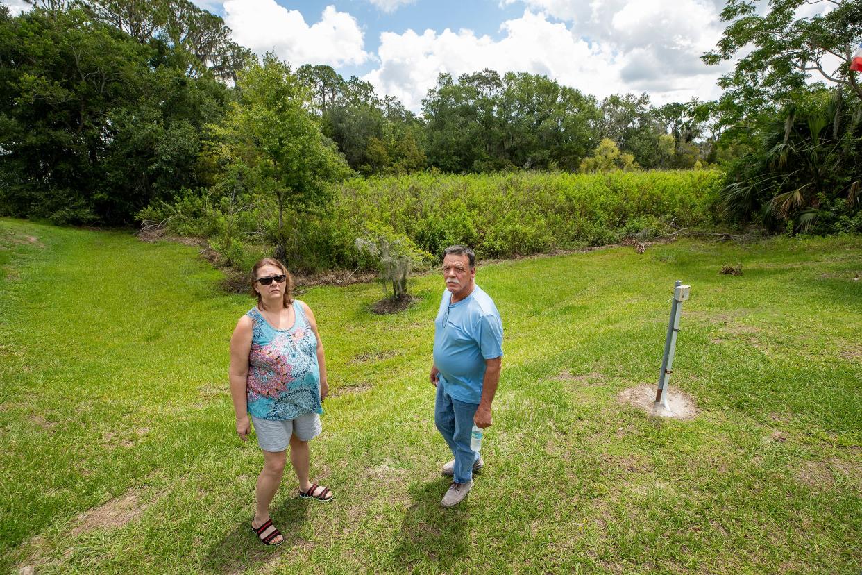 Imperial Lakes residents Joan Pezzani and David Kolodziej stand near the edge of an overgrown retention pond behind Kolodziej's home at 4130 Old Colony Road in Mulberry. Residents in the area are pressuring the county to help with flooding along Imperial Lakes Boulevard.