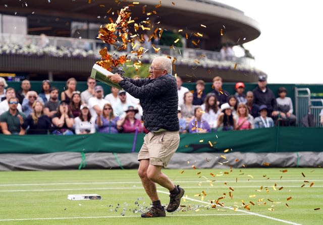 A Just Stop Oil protester on throws confetti and jigsaw pieces on to the grass and causes a delay during Katie Boulter's match on Court 18