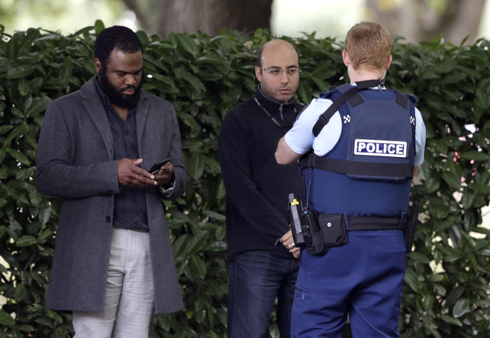 A police officer photographs witnesses near a mosque in central Christchurch, New Zealand, Friday, March 15, 2019. Multiple people were killed in mass shootings at two mosques full of people attending Friday prayers, as New Zealand police warned people to stay indoors as they tried to determine if more than one gunman was involved.(AP Photo/Mark Baker)