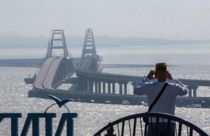 A man takes a photo of the Kerch Bridge, which links the illegally annexed Crimean Peninsula to Russia, on Oct. 8, 2022. (Photo by -/AFP via Getty Images)