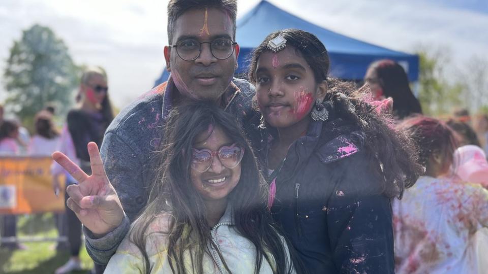 Sri Tedla with his two daughters covered in the coloured powder
