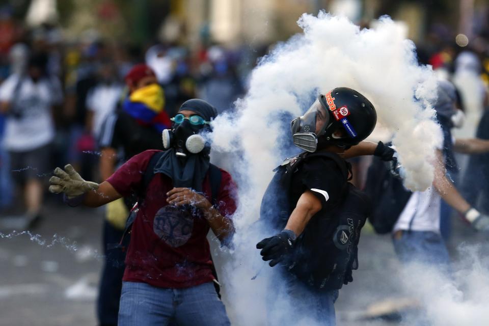 An anti-government protester throws a gas canister at the police during clashes at Altamira square in Caracas