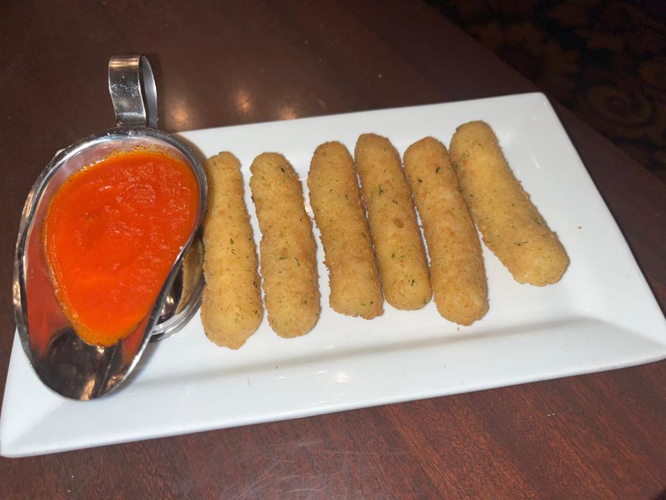 mozzarella sticks from tutto italia with red dipping sauce on left side of plate