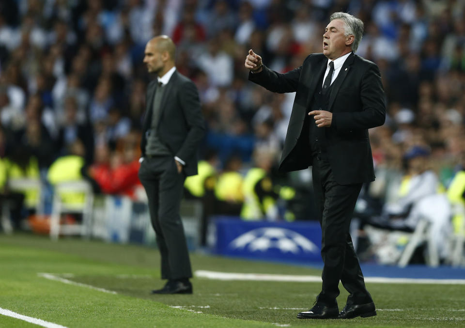 Real's coach Carlo Ancelotti gestures to his players next to Bayern head coach Pep Guardiola, left, during a first leg semifinal Champions League soccer match between Real Madrid and Bayern Munich at the Santiago Bernabeu stadium in Madrid, Spain, Wednesday, April 23, 2014. (AP Photo/Andres Kudacki)