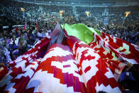 Women wave a huge Belarusian State flag as they listen to Belarusian President Alexander Lukashenko during a women's forum in Minsk, Belarus, Thursday, Sept. 17, 2020. President Alexander Lukashenko's decision to close the borders with Poland and Lithuania underlines his repeated claim that the massive wave of protests is driven by the West and comes amid increasing criticism from the United States and the European Union. (TUT.by via AP)