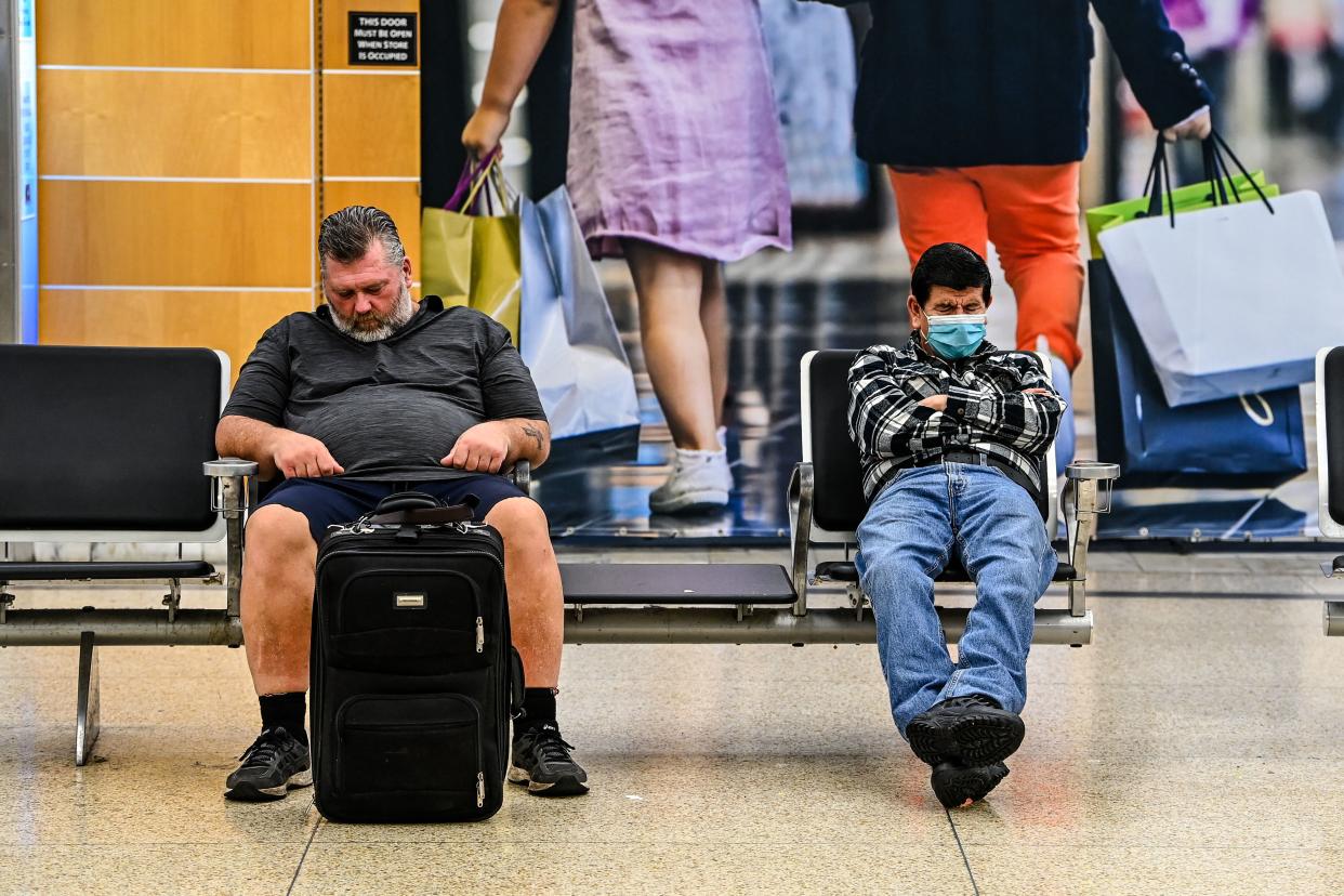 Commuters with and without face mask sit inside the Miami International Airport on April 19, 2022. (Photo by CHANDAN KHANNA/AFP)