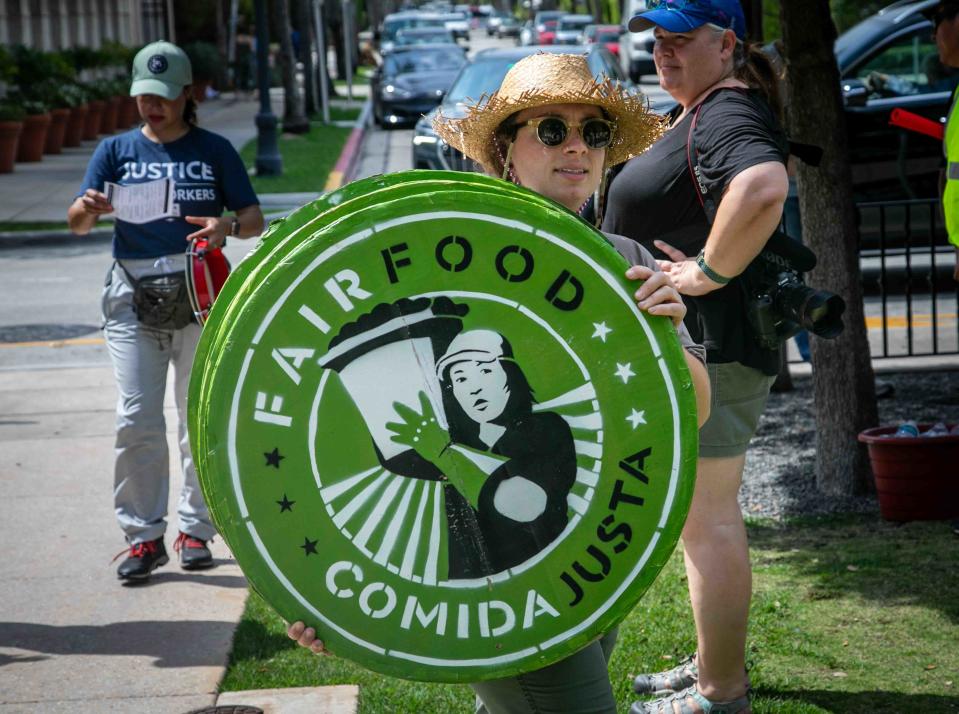 A woman carries a stack of Fair Food signs behind Palm Beach Town Hall on Friday during the start of a three-day Farmworkers Festival.